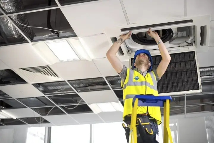 Technician performing office ceiling maintenance